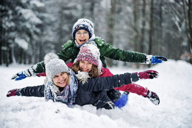 famille jouant à la neige dans une belle forêt un jour d’hiver - group of people teenager snow winter photos et images de collection