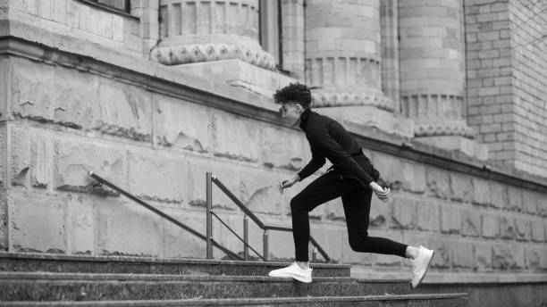 the young male model is running on the stairs. black and white image. - running athlete staircase teenager imagens e fotografias de stock