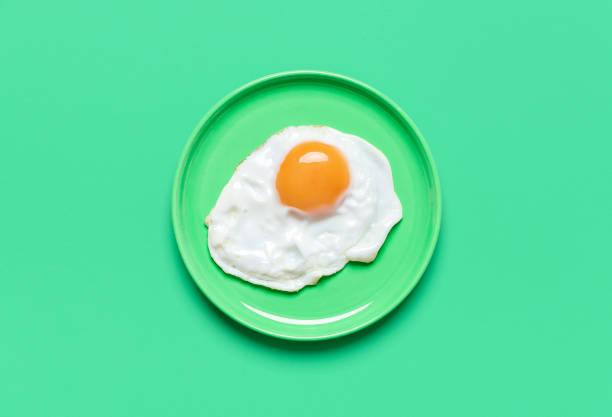spiegelei auf minimalistischem auf grünem grund, blick von oben - eggs fried egg egg yolk isolated stock-fotos und bilder