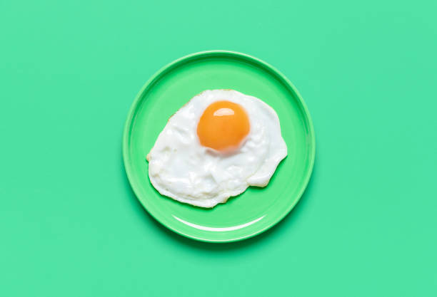 Fried egg on minimalist on a green background, view from above
