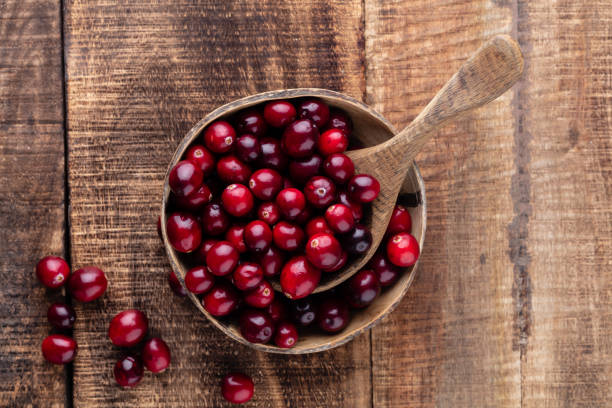 istock Red cranberries on wooden background. Brries in a bowl. 1387429607