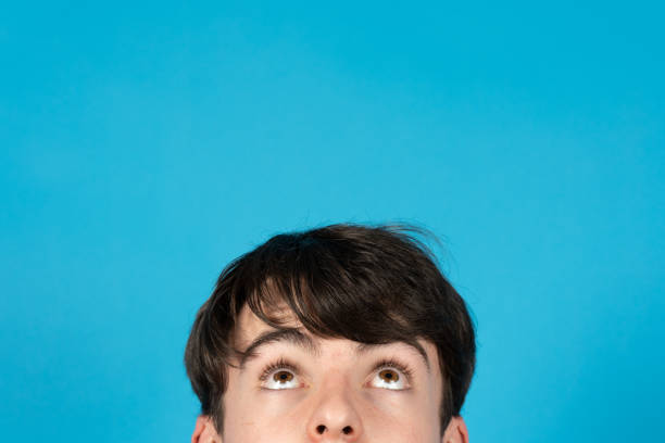 Teenager boy getting ideas and day dreaming. Half portrait of adolescent looking up to copy space.