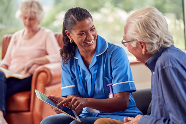 디지털 태블릿을 사용하여 여성 간호사 또는 간호 노동자에게 이야기하는 남자와 집에서 노인 부부 - social services 뉴스 사진 이미지