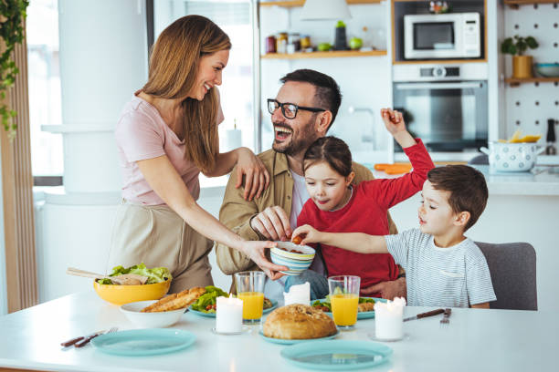 glückliche familie, die zusammen in der küche isst. - two parent family indoors home interior domestic kitchen stock-fotos und bilder