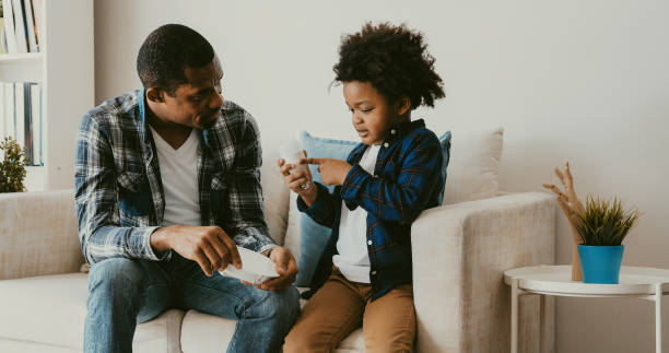 father teaching energy saving to his son. - household equipment light bulb compact fluorescent lightbulb lighting equipment imagens e fotografias de stock