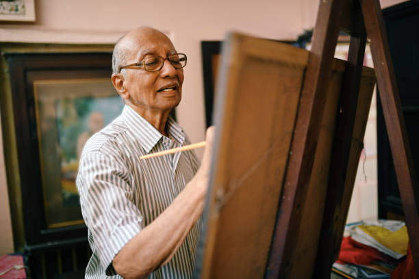 Senior artist painting on canvas in his studio