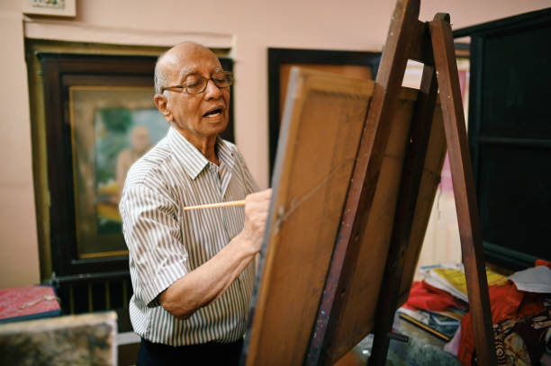 istock Senior artist painting on canvas in his studio 1387434542