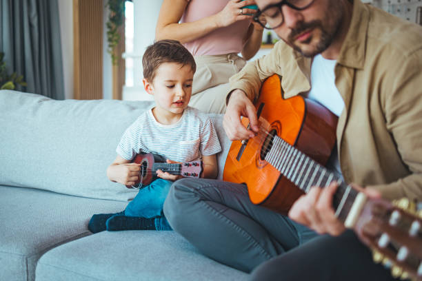 istock Father teaching his son to play on guitar at home. 1387434629
