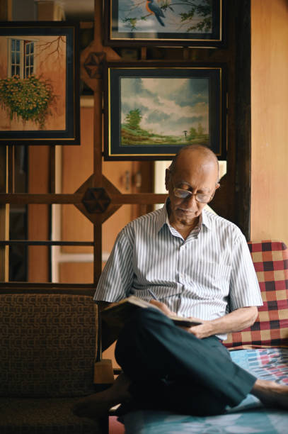 istock Senior man sitting next to window and writing in a diary 1387434704