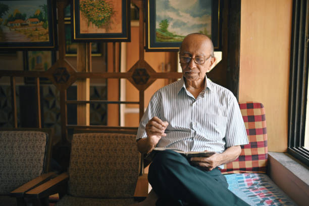 istock Senior man sitting next to window and writing in a diary 1387434906
