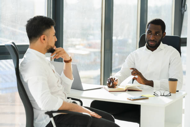 istock Black man interviewing new employee in company office 1387436596