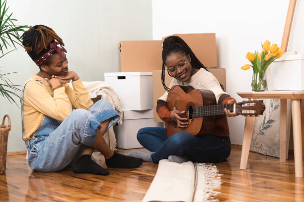 istock Two African roommates playing a guitar and relaxing while moving in 1387436927
