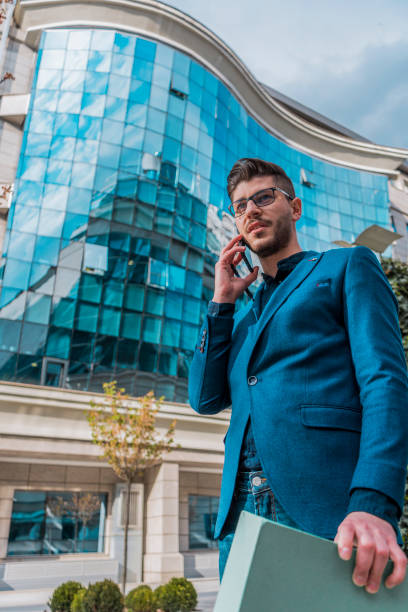 istock Cheerful businessman with green folder talking on mobile phone 1387437753