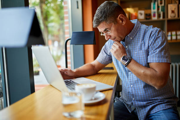 Mature businessman working on laptop in cafe stock photo