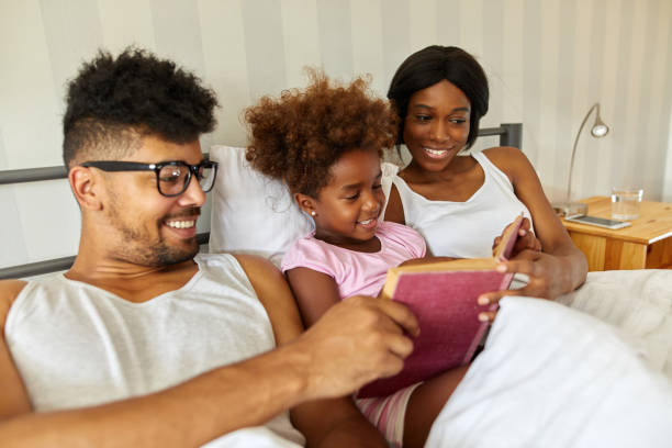 istock Happy family reading an interesting book in bed 1387439472