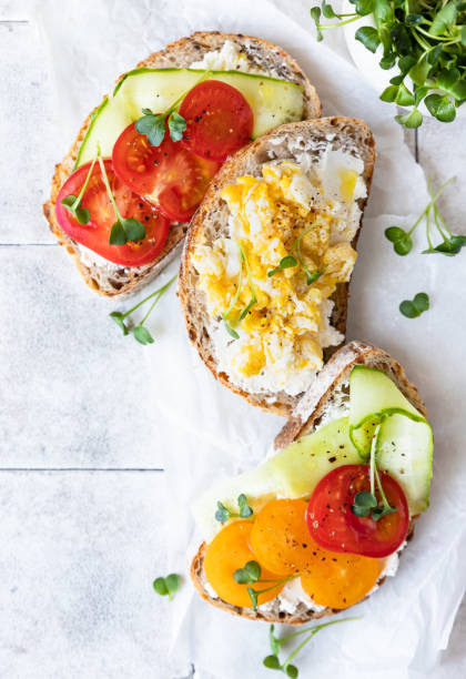 istock Healthy breakfast or lunch with sourdough bread, cream cheese, vegetables and scrambled eggs, tiled background. Top view. 1387439938