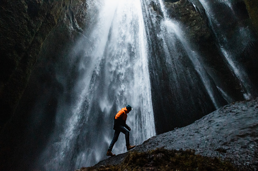 The male traveler standing against the majestic Gljufrabui Waterfall in Iceland