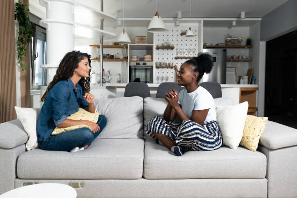 istock Two young friends and roommates sitting on sofa in their modern cozy studio apartment talking about men. Females conversation about relationships and goals for the future. 1387444502