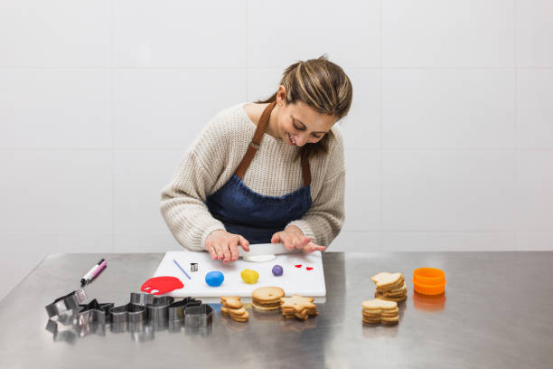istock Cheerful female baker rolling gum paste in bakery 1387445473