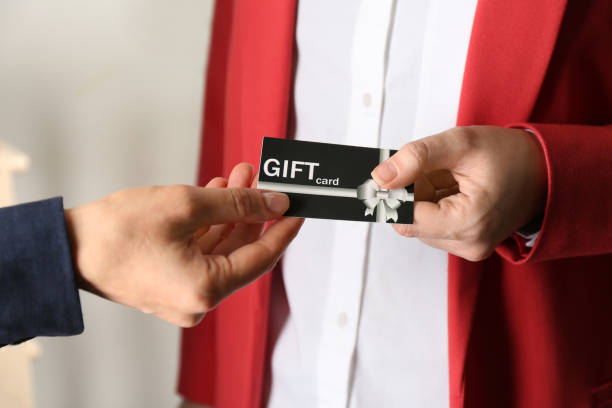 istock Women with gift card on blurred background, closeup 1387446039