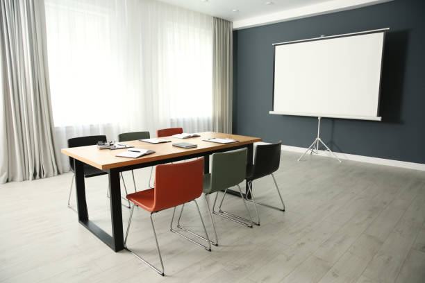 istock Modern meeting room interior with large table and projection screen 1387446600