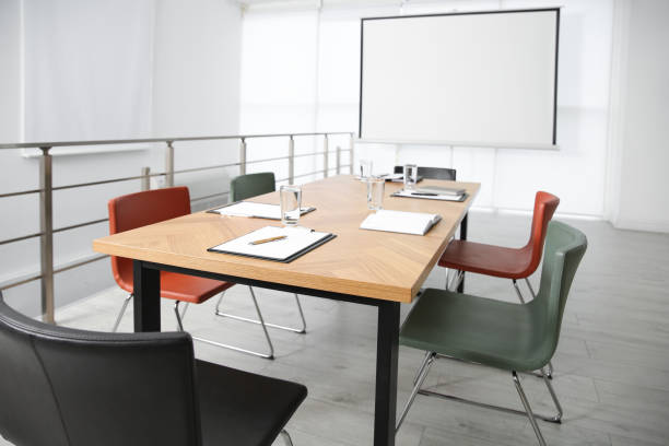 istock Modern meeting room interior with large table and projection screen 1387446604