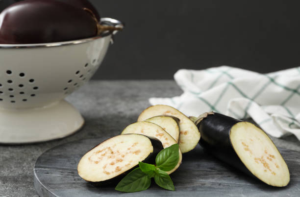 istock Cut purple eggplant and basil on grey table, closeup 1387446887