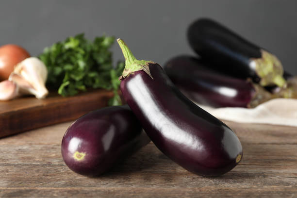 istock Ripe purple eggplants on wooden table, closeup 1387446903