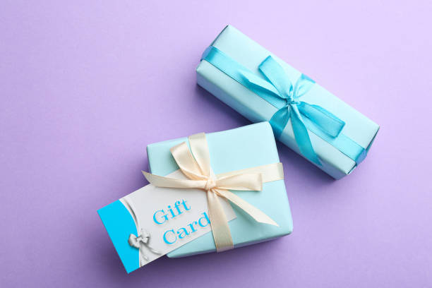 istock Gift card and presents on violet background, flat lay 1387446976