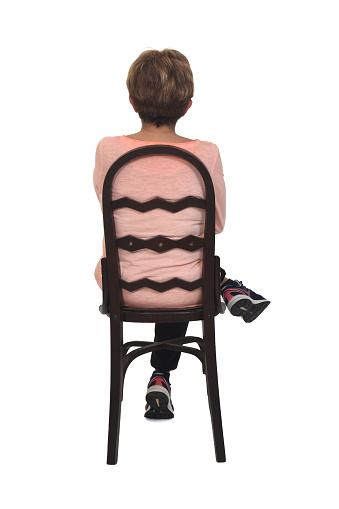 back view of senior woman sitting on chair legs and arms crossed white background