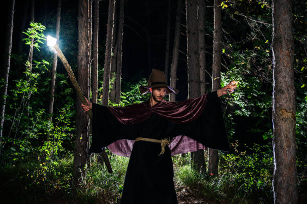 istock Young wizard showing magic on Halloween night with his magic wand 1387450483