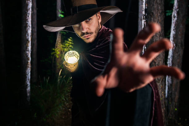 Young magician in costume perform acrobat moves in dark forest