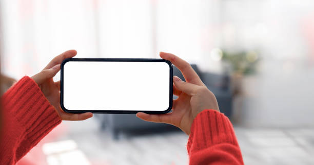 istock Mockup image of a woman holding and using mobile phone with blank desktop screen in horizontal view. 1387451477