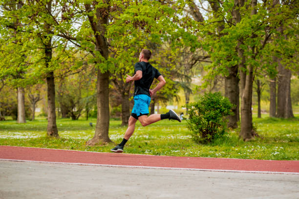 istock Runners training, young man running exercising concentrated on road in beautiful nature 1387451849