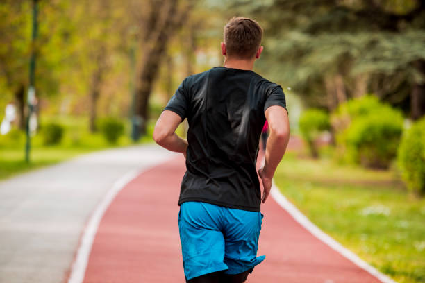 istock Fit man jogging, running, exercising or stretching outdoors in park or nature 1387451852