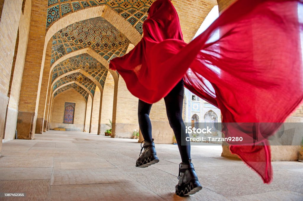 Woman in red cloak running traditional Iranian style courtyard Iran Stock Photo