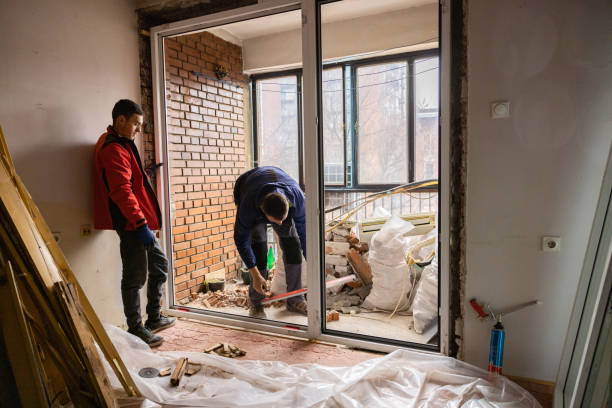 istock Two Male Workers Measuring Frame of Window 1387453316