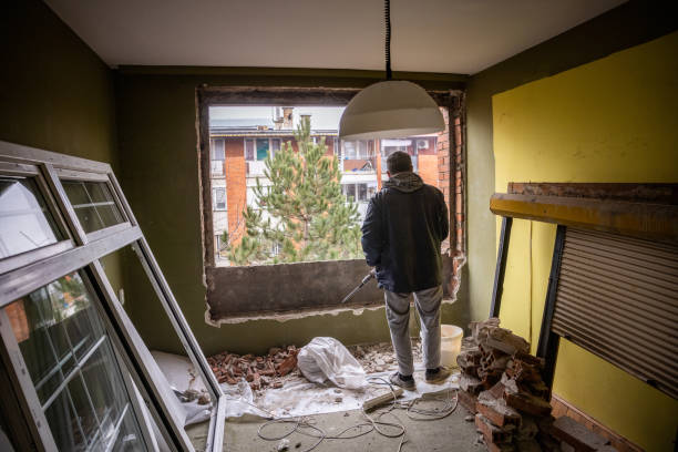 Male construction worker is observing the hole in the wall of the window.