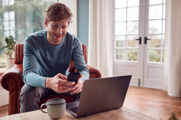 istock Man Working From Home Using Laptop And Mobile Phone 1387456245