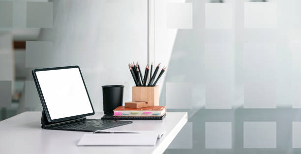 istock Creative workspace with tablet computer and supplies on wooden table, blank screen for productdisplay. Home office background concept. 1387456481
