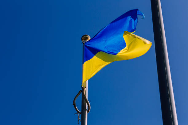 istock Ukraine flags flying in the wind against blue sky 1387457820