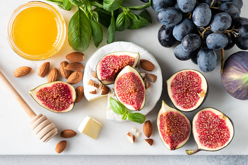 Cheese platter with brie or camembert, figs, grapes, nuts and honey. Top view. Gourmet appetizer or wine snack set