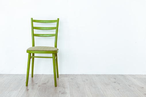 Conceptual empty green wooden chair with white wall and gray wooden floor and copy space. Mortgage and repair