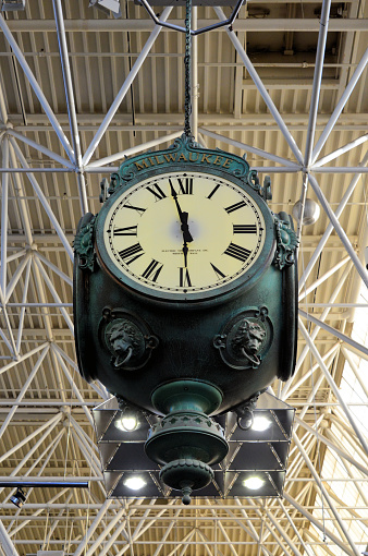 A white vintage round clock hanging on the roof of a train station.