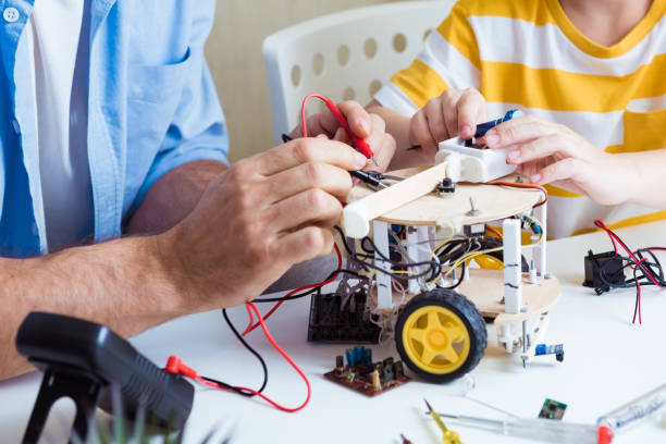 istock Close up of construction workflow of electronic mechanism with microcontroller at junior robotics club. Collective work creation of diy electronics, modern technologies, innovation and science concept 1387459860