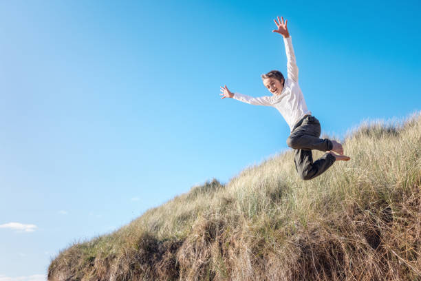 istock Boy running and jumping over sand dunes on beach vacation background 1387460976
