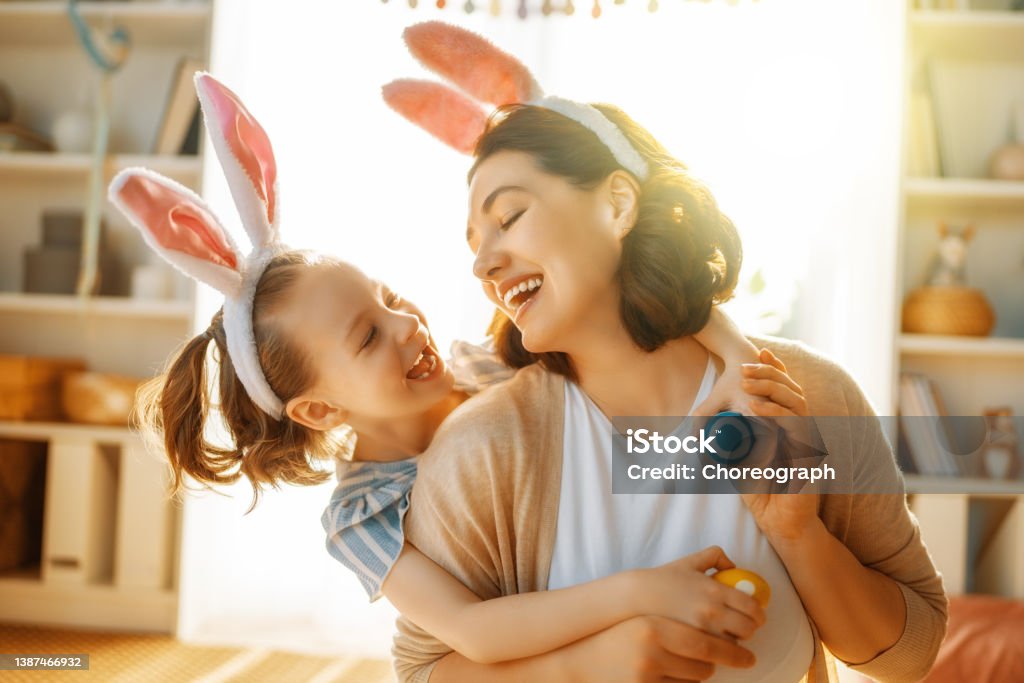 Family celebrating Easter Happy holiday! Mother and her daughter with painting eggs. Family celebrating Easter. Cute little child girl is wearing bunny ears. Easter Stock Photo