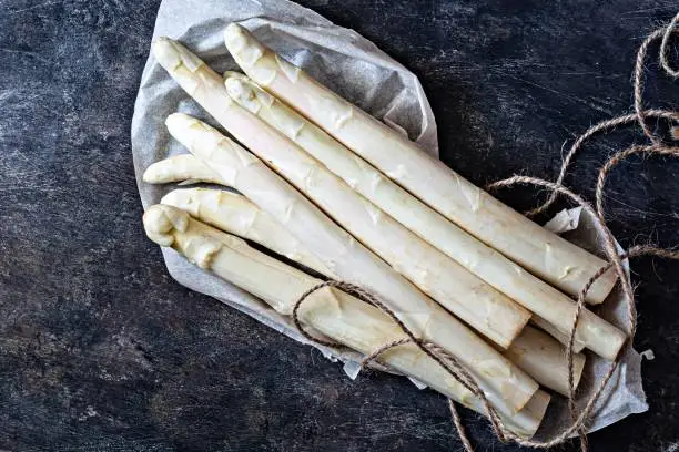 Raw white asparagus on a dark textured background. Raw food concept.