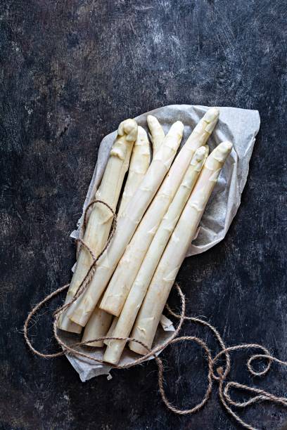 istock Raw white asparagus on a dark textured background. Raw food concept. 1387469322