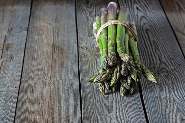 Green asparagus on a dark wooden background. Raw food concept, place for copy space.